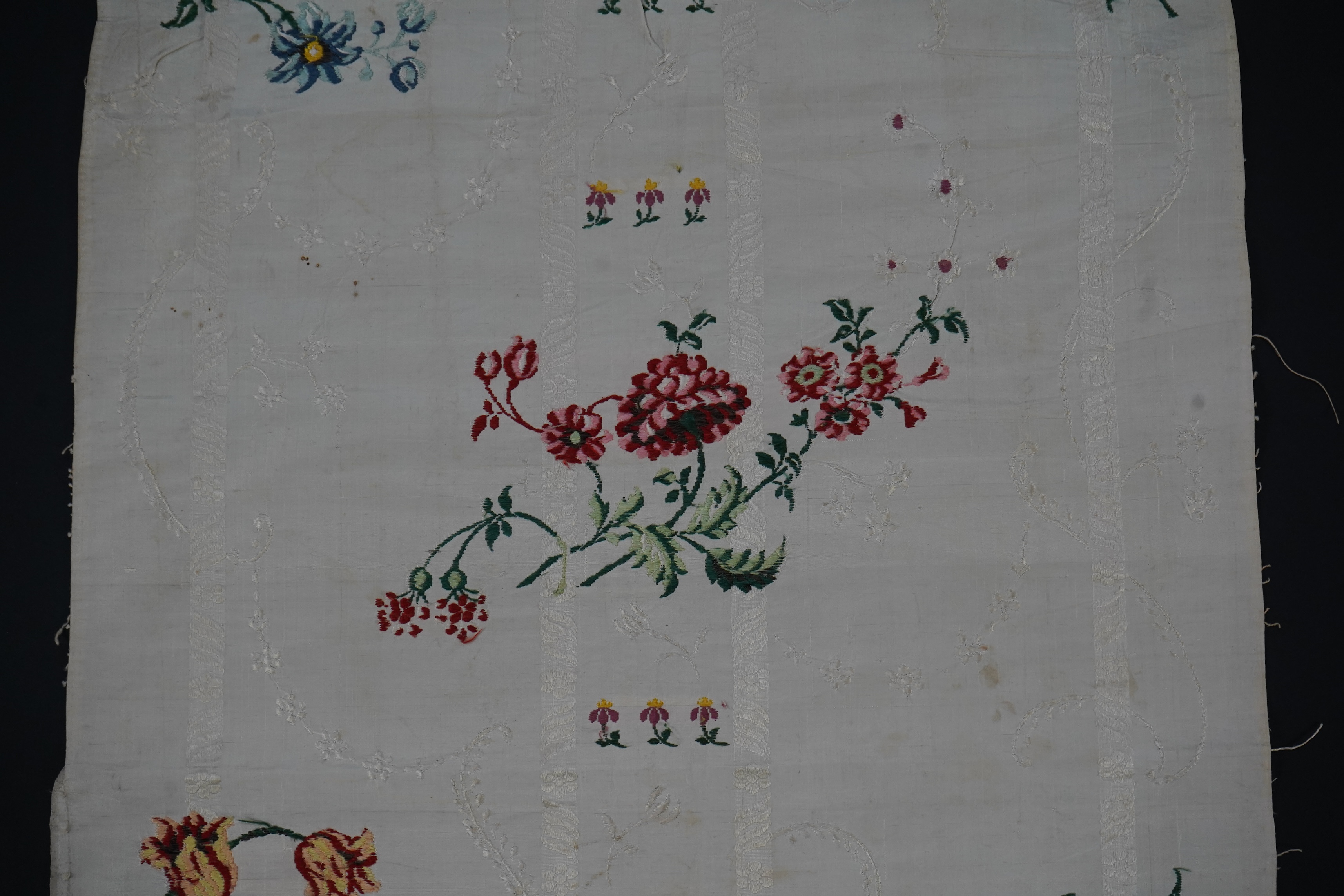 A length of 18th century short loom hand woven Spitalfields silk dress fabric, woven in cream silk with all over multicoloured spot floral motifs in a large repeat. 82cm repeat, total length of fabric 100cm x 48.5cm wide